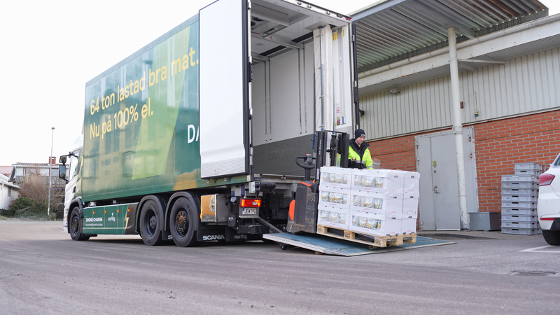 Bilden föreställer en lastbil där en person håller på att lasta av matvaror